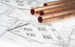 The blueprints for a house with copper pipes on top of them.