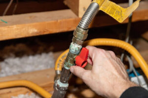 A hand turning the safety shut off valve on a natural gas pipe.