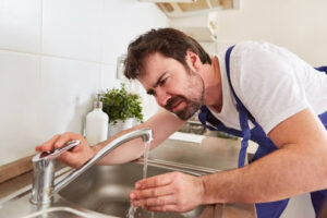 A plumber inspecting a kitchen faucet.