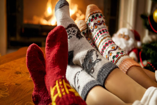 A family's socks in front of a fireplace.