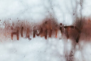 The word "humidity" written on the condensation of a window.
