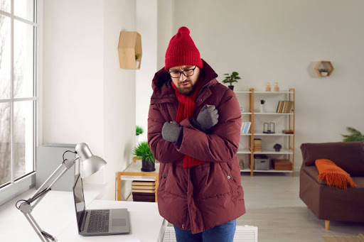 Man layered up in winter clothes because furnace is broken.